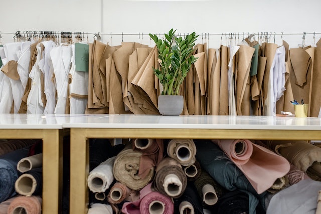 Fabric rolls with clothing samples hanging on rack