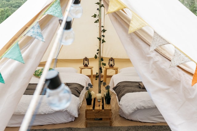 Glamping tent with beds, table lamps and potted plants