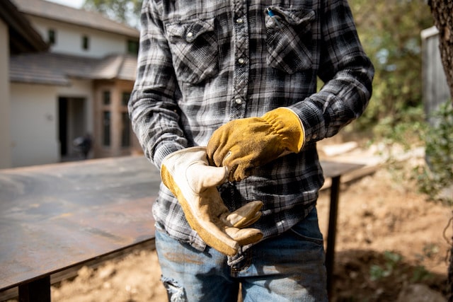 Man in grey flannel shirt pulling on gloves