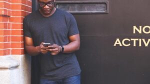 Man leaning against a wall and looking at his phone