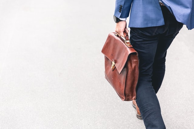 Man with briefcase walking around the camera