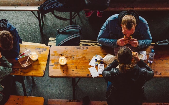 Overhead-view-of-people-eating-at-wooden-tables-outside