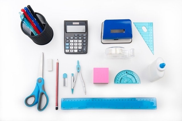 Overhead view of school supplies laid out on a white background