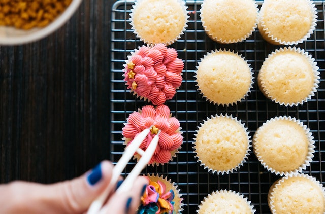 Person decorating cupcakes with intricate designs