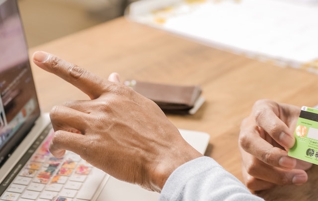 Person pointing to laptop screen with credit card in hand