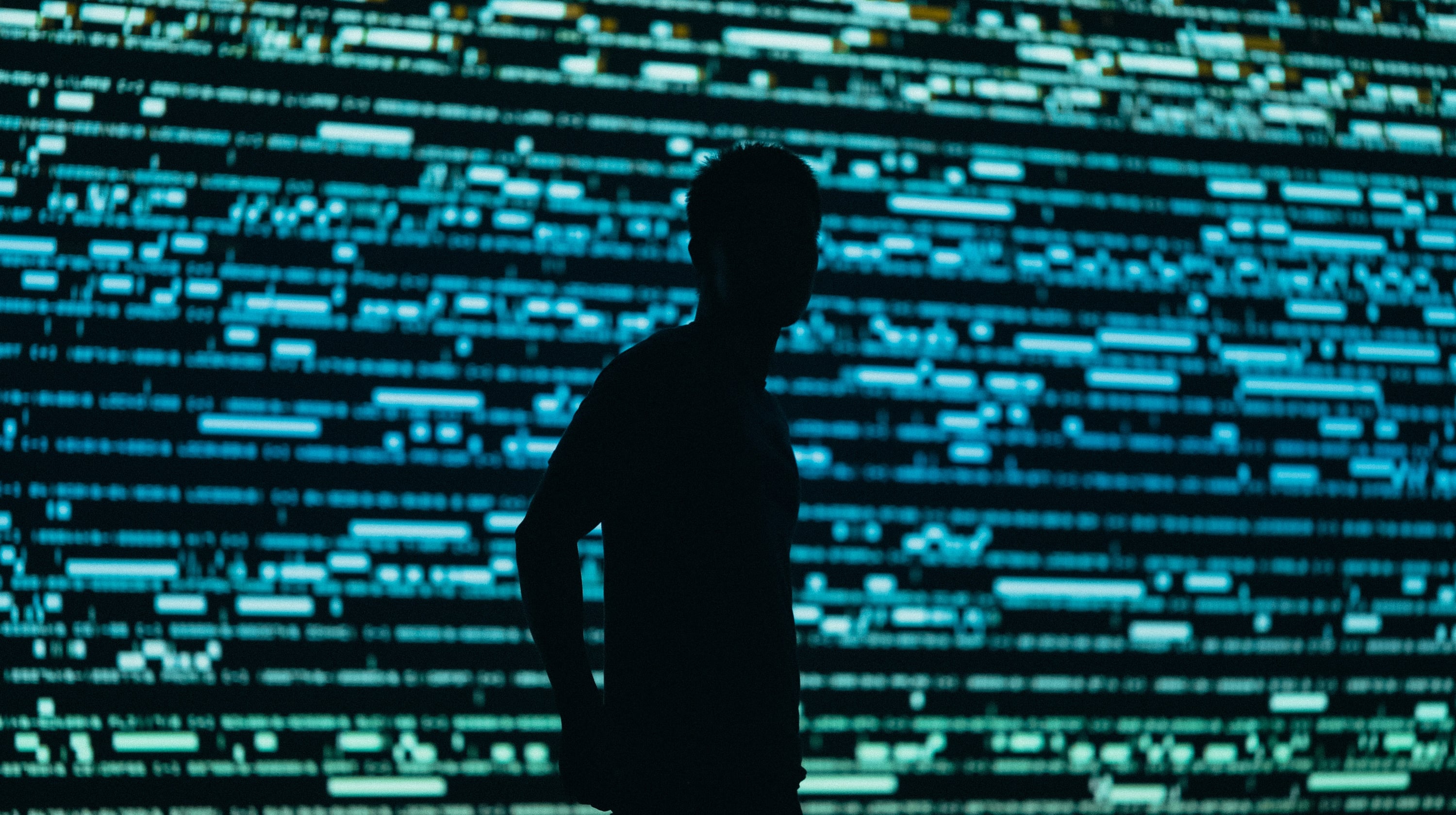 Shadowy person backlit by a lighted wall