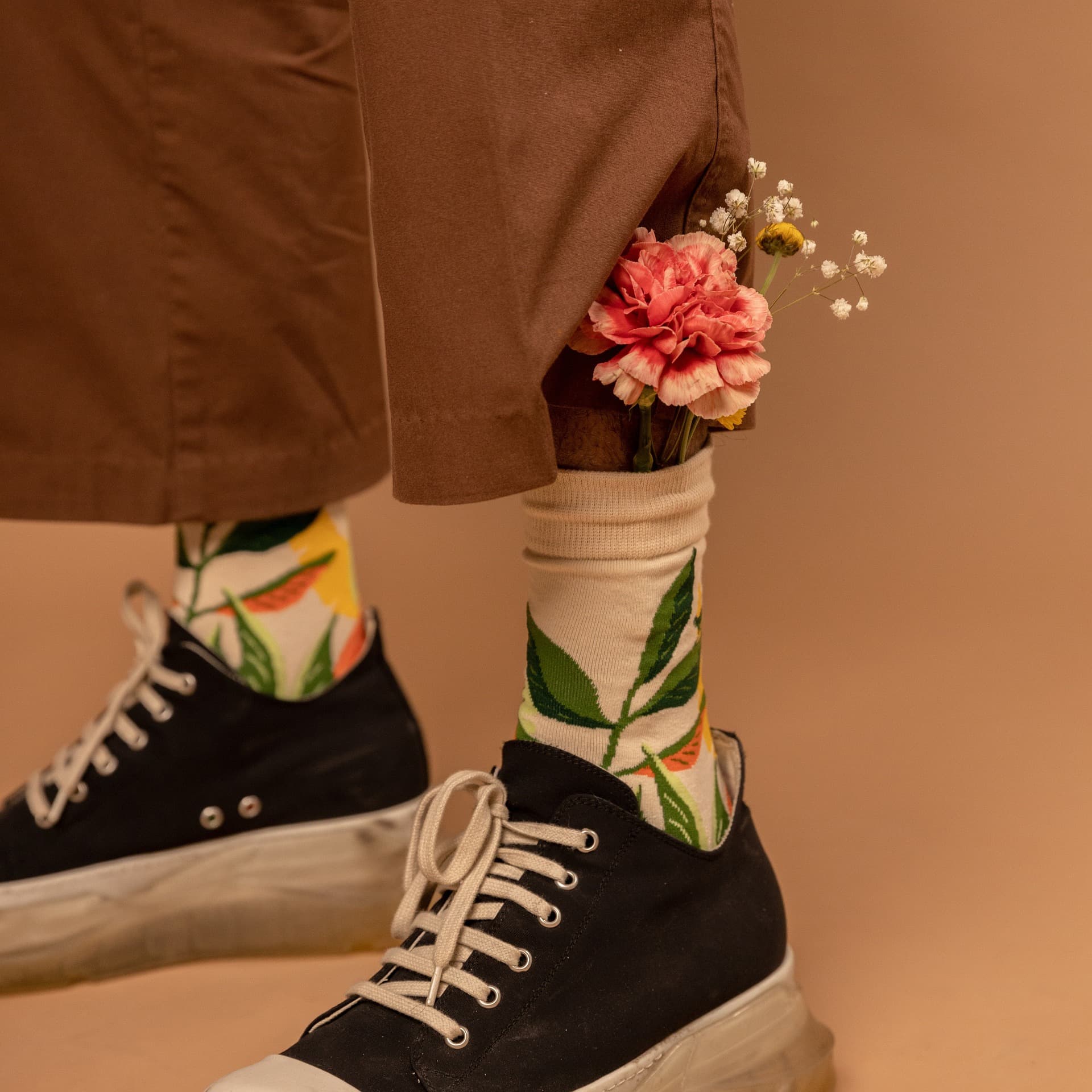 Person wearing floral socks with black trainers