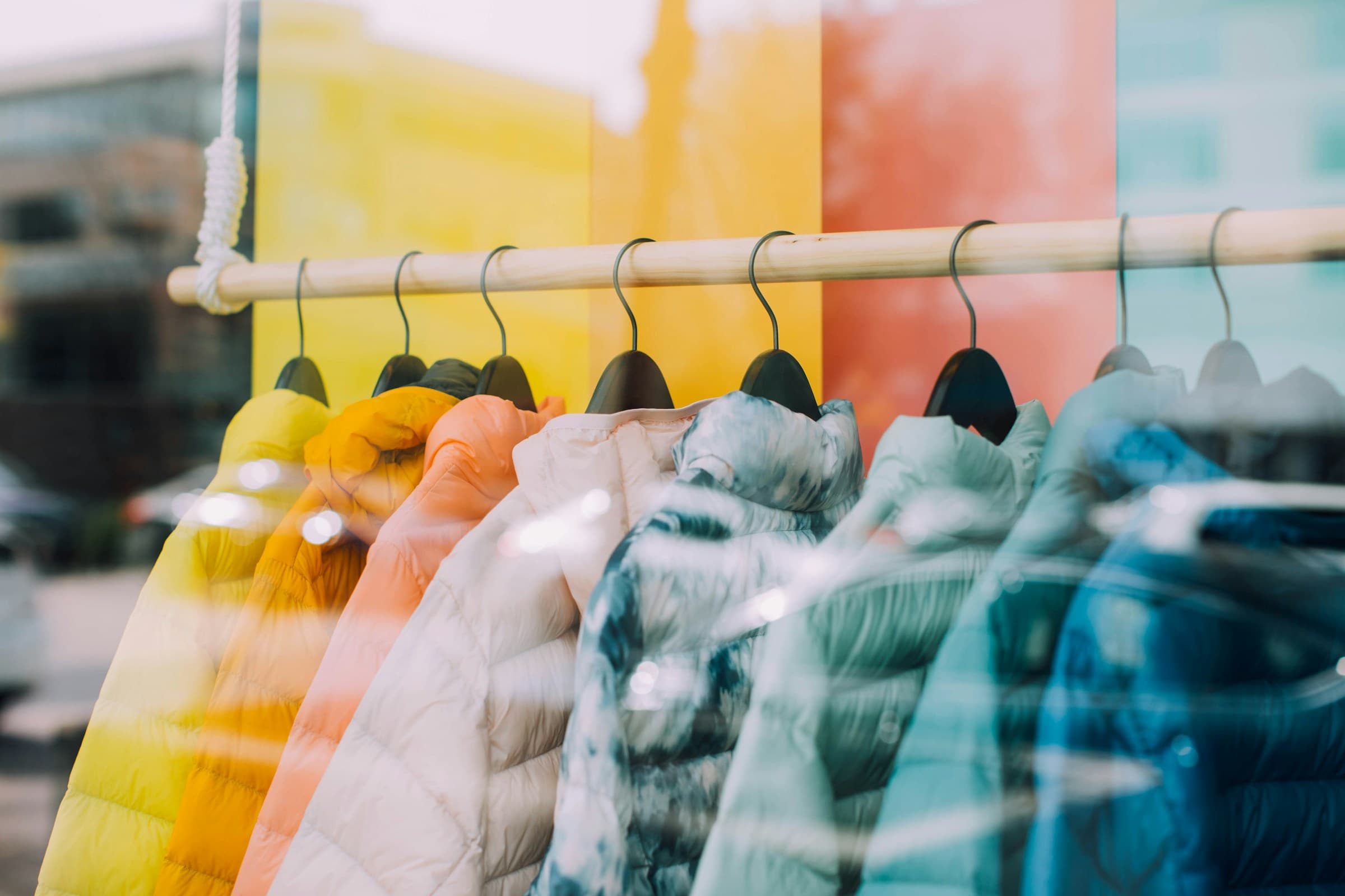 Rack of colourful coats seen through a shop window