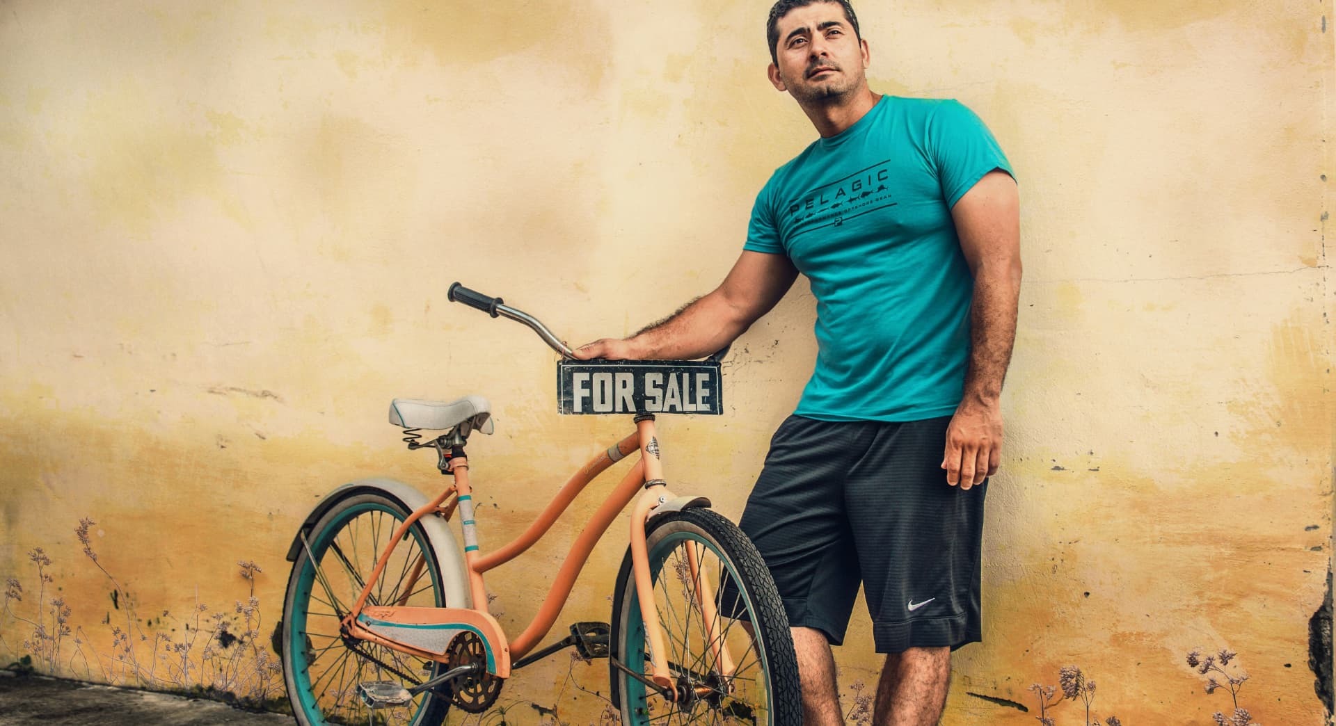 Man standing next to a bike with a for sale sign on it