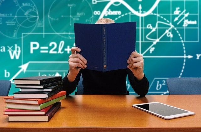 Teacher sitting at a desk in front of a blackboard