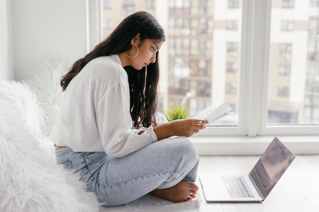 Woman looking at papers in front of an open laptop