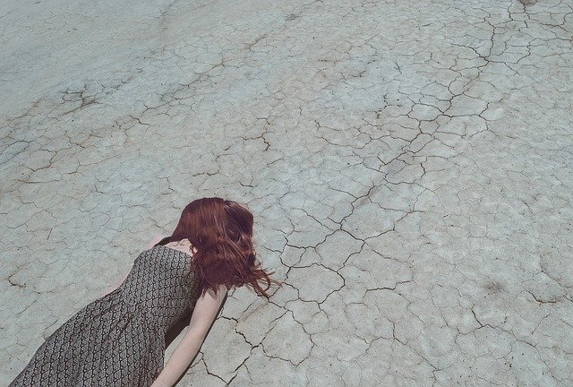 Woman lying on dry and cracked earth