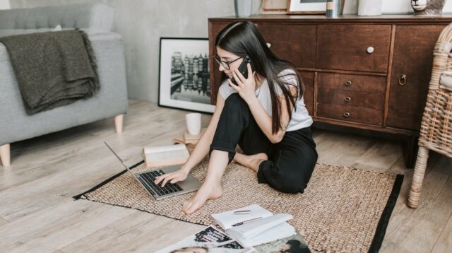 Woman sitting on the floor with a laptop and phone