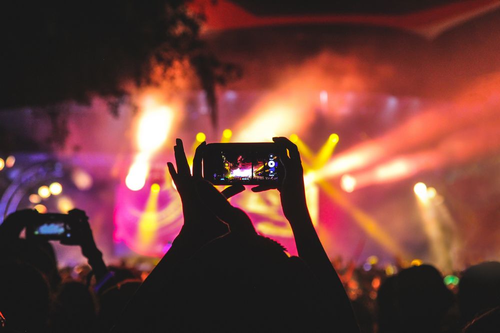 Imagen de una chica sujetando un móvil grabando un concierto, para subirlo luego a una red social como Vine