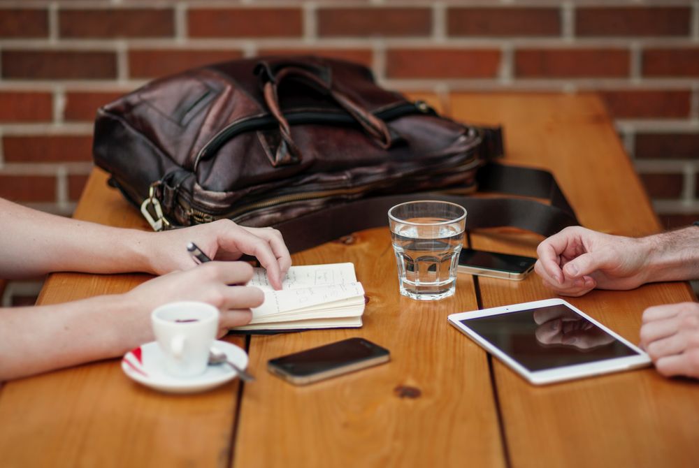 Imagen de dos personas charlando con un café en una mesa de madera