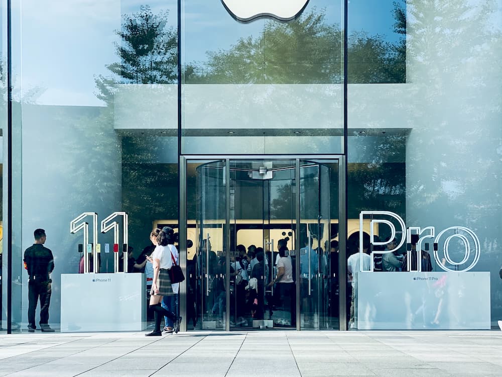 Imagen del exterior de una tienda Apple donde se anuncia el lanzamiento del iPhone 11 Pro con muchos clientes esperando.