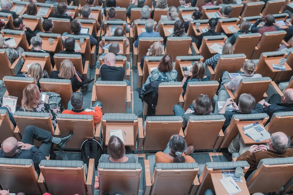 Imagen de gente reunida en una sala de conferencias, asistiendo a un ejemplo de comunicación corporativa de una empresa.