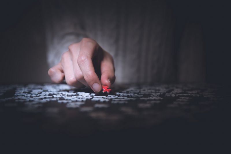 Imagen de un hombre sujetando una pieza de puzzle de color rojo