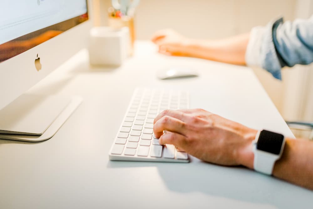 Imagen de un hombre escribiendo usando el teclado de in iMac.