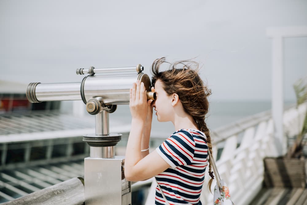 Imagen de una mujer observando el horizonte a través de un telescopio