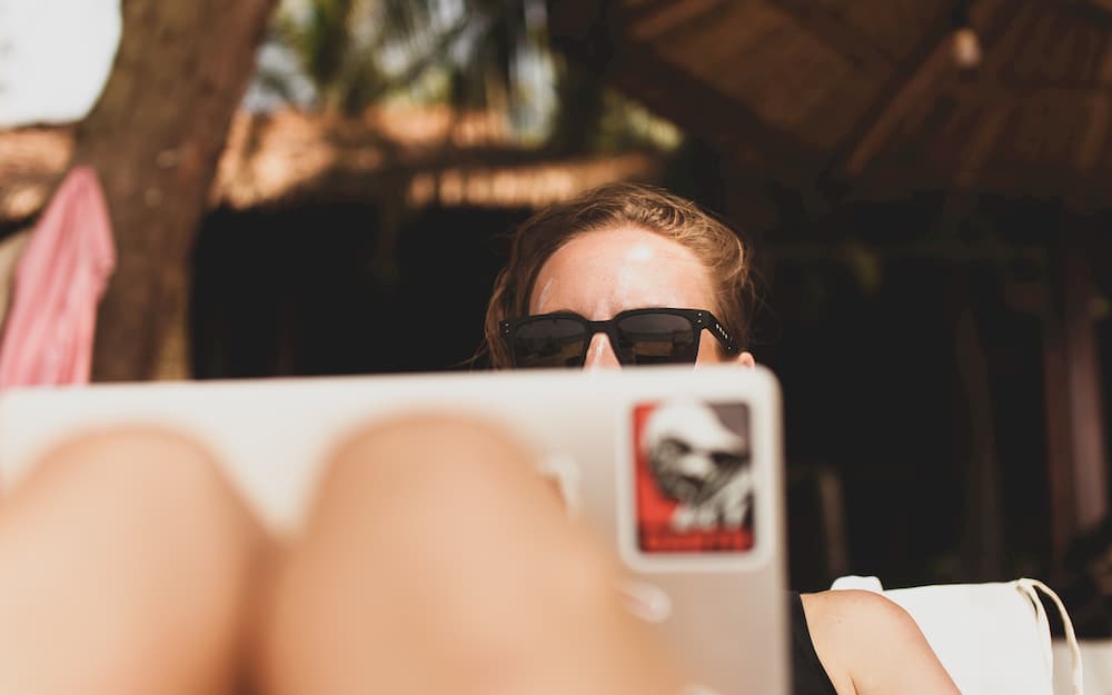 Imagen de una mujer usando su portátil fuera de casa, usando las aplicaciones Office 365 para acabar sus proyectos