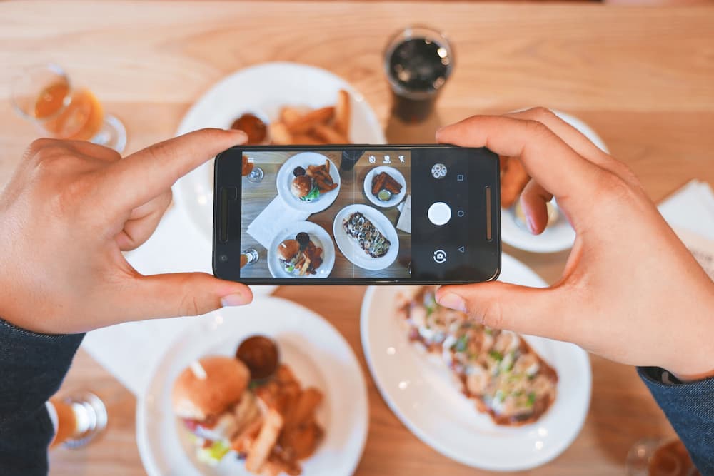 Imagen de una mujer fotografiando comida con su teléfono