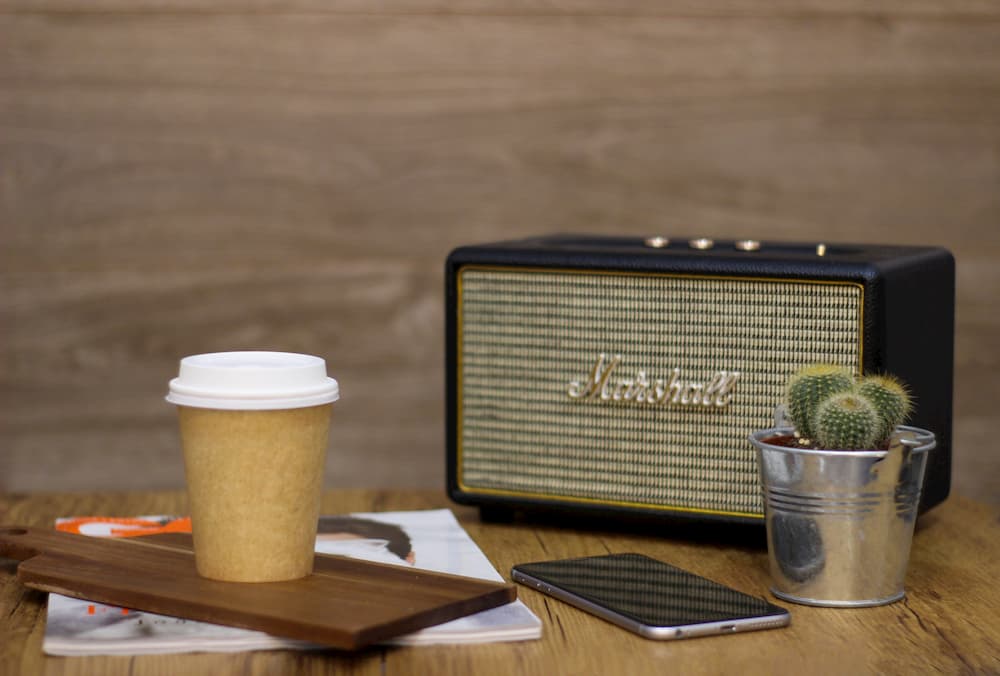 Imagen de un smartphone al lado de un altavoz Marshall con Bluetooth.