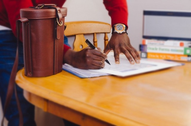 Un hombre de raza negra firmando un contrato en una mesa