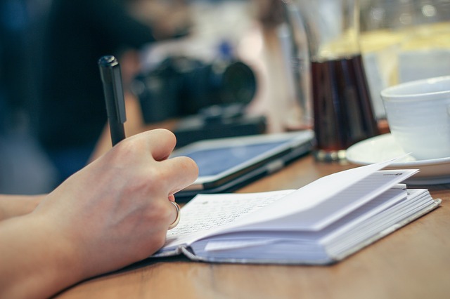 Imagen de una persona escribiendo en una libreta, revisando cómo funciona el IVA en el comercio online