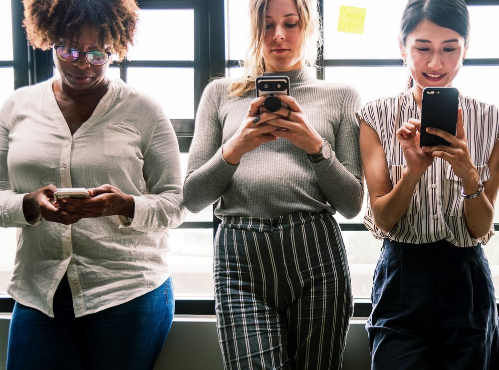 Imagen de tres mujeres usando sus teléfonos móviles