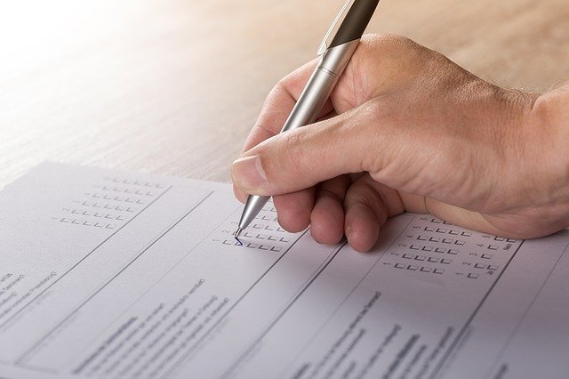 Hand marking a checkbox on a survey with a pen