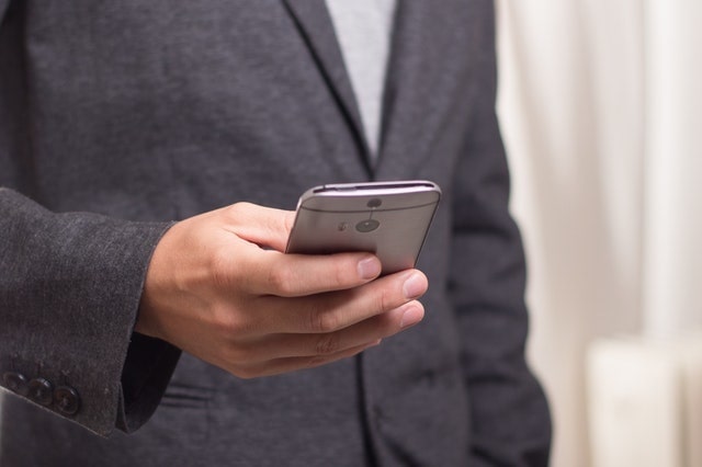 Man in a gray suit coat using a smartphone