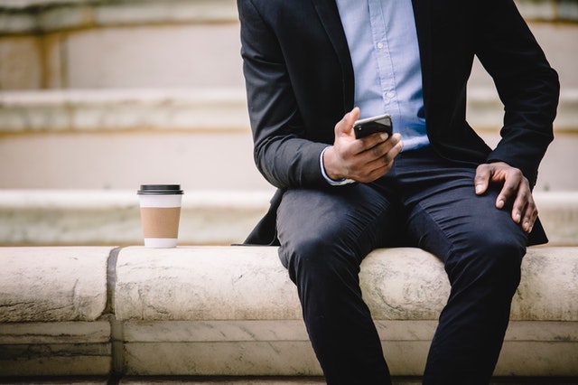 Man Sitting Outside Looking at His Phone