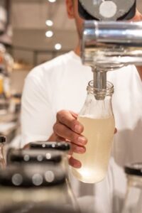 Person Filling Glass Bottles from a Tap