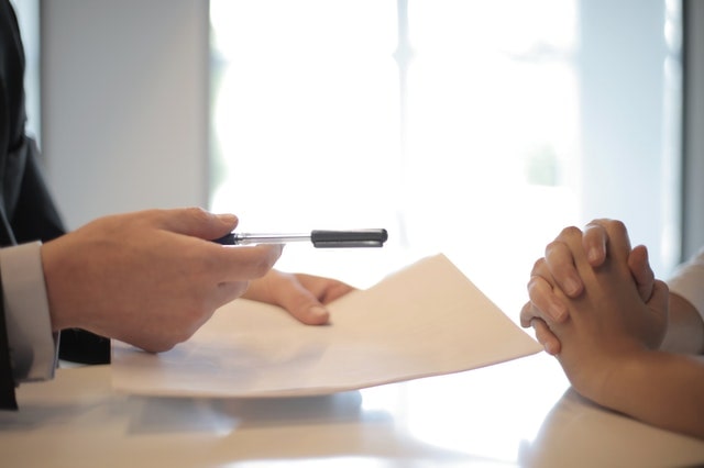 Person offering a contract and pen to another