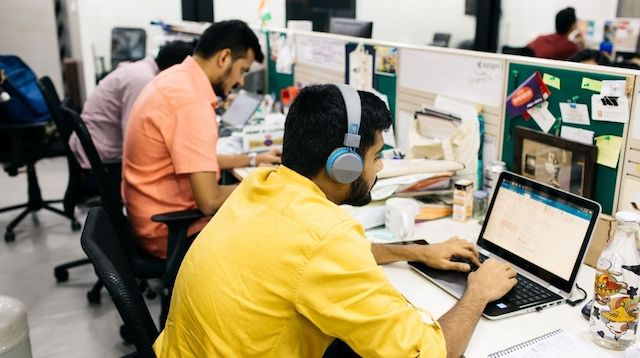 Row of three men working at computers