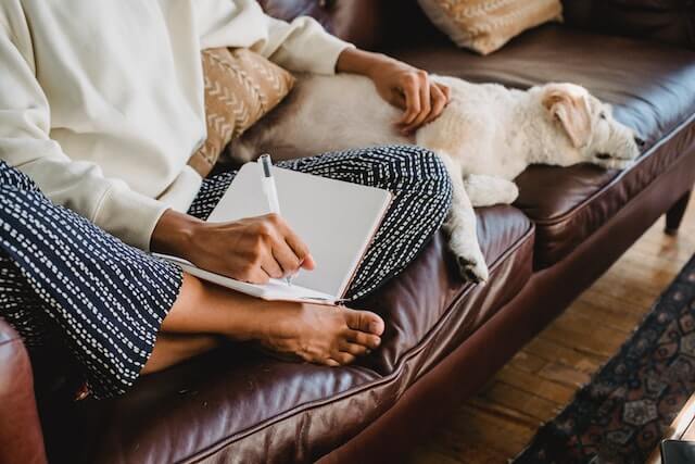 Woman jotting notes in notebook on a couch