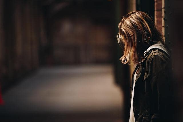 A young woman standing in a dimly lit hallway