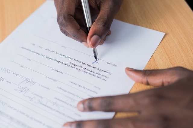 Close-up of a persona signing a paper form