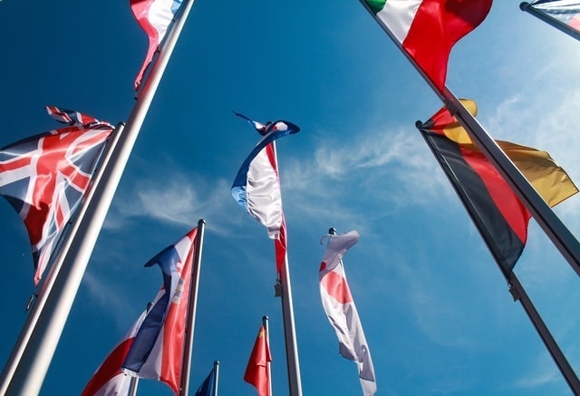 Country flags photographed against a blue sky