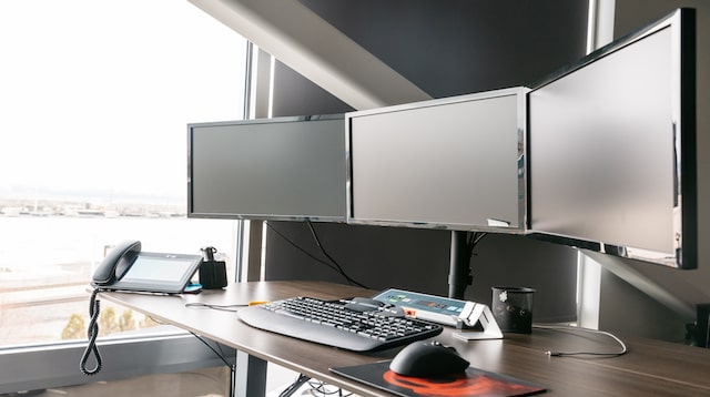 Desktop computer with three screens on a desk