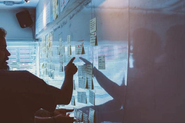 Developer pointing at notes on a whiteboard