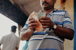 Man counting rupees outside a shop