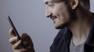 Man smiling as he looks at his phone