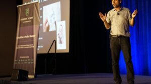 Man standing on a stage making a presentation