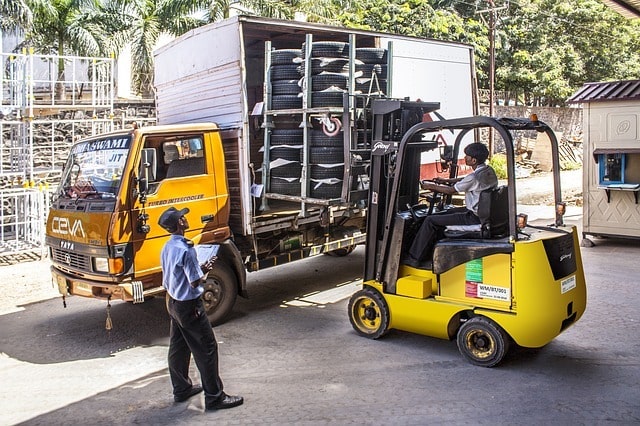 Men unloading tires from a truck with a forklift