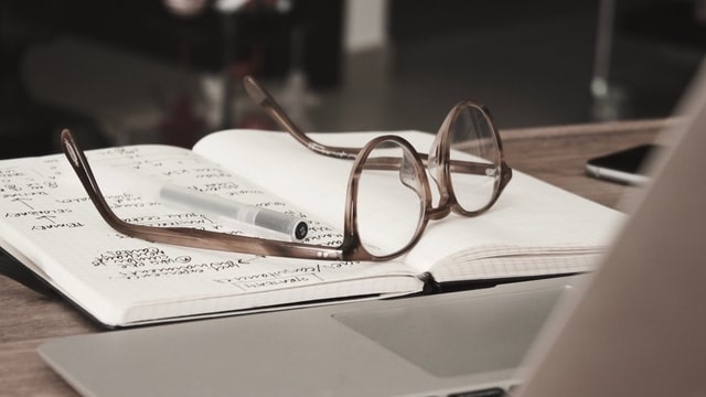 Pair of glasses sitting atop a notebook