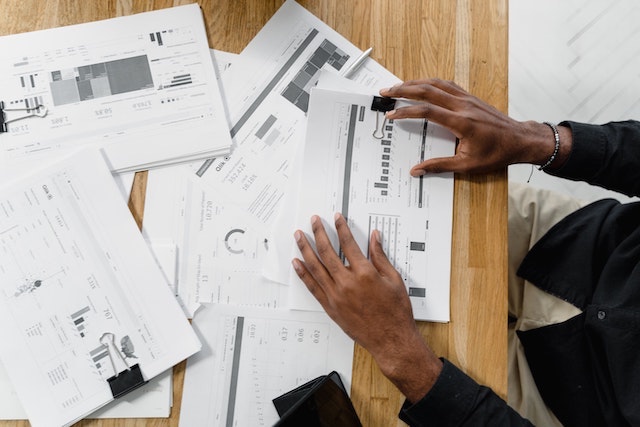 Person shuffling through reports on a desk.