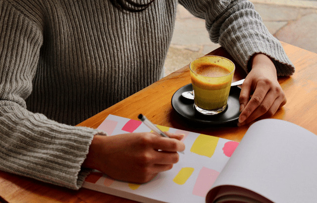 Person at desk with a pen writing on pad