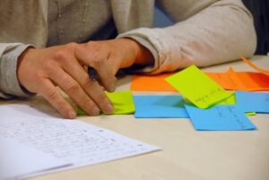 Person writing on brightly coloured notes